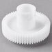 A white plastic gear with a hole on a gray surface.