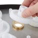 A hand holding a white plastic gear.