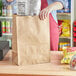 A woman putting a bag into a brown paper barrel sack.