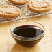 A bowl of Grandma's molasses next to cookies.