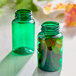 A close-up of a green PET packer bottle with a few green caps.