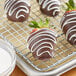 Chocolate covered strawberries on a cooling rack drizzled with Alpine Bright White Vanilla Coating.