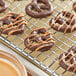 Chocolate covered pretzels on a metal cooling rack with Alpine Peanut Coating Wafers.