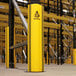 A yellow and black A-Safe RackGuard on a pole in a warehouse.