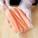A hand holding a plastic bag of carrots.