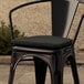 A black Lancaster Table & Seating chair with a black fabric cushion.