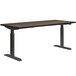 A HON Florence Walnut and Black height-adjustable desk with a metal frame.