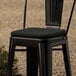 A Lancaster Table & Seating black metal chair with a black cushion on a black seat.