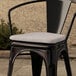 A Lancaster Table & Seating Alloy chair with a gray fabric cushion on it.