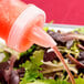 A GET Juice Pour Lid pouring liquid from a bottle onto a salad.