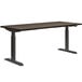 A HON Florence Walnut and Black height-adjustable desk with a metal frame.