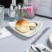 A Tuxton eggshell triangle china plate with food and a glass of water on a table.