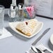 A Tuxton triangle china plate with a pastry on it with a fork and knife.