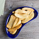 A Tuxton cobalt blue china crescent dish with French fries on it.