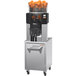 A Zummo commercial juicer with oranges in a load basket.