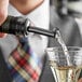 A man using an Acopa black liquor pourer to pour liquid into a glass.