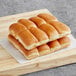 Nathan's Famous beef slider buns on a table with a stack of bread.