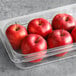 A plastic container with Fresh Wax-Free Red Delicious Apples in it.