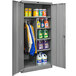 A Hallowell gray steel combination cabinet with solid doors filled with cleaning supplies.