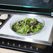 A salad bowl in a Cambro salad bowl holder on a counter.