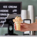 A hand holding a JOY flat bottom cake cone filled with ice cream.