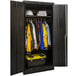 A black metal wardrobe cabinet with solid doors filled with clothes and a toolbox.