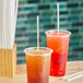 Two plastic cups with clear wrapped straws on a table.