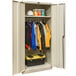 A Hallowell tan metal wardrobe cabinet with solid doors holding clothes and tools.