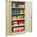 A Hallowell tan storage cabinet with solid doors filled with various items.