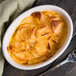 A Hall China oval baker dish filled with food and a fork.