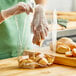 A person in gloves putting bread in a Choice standard-duty plastic food bag.