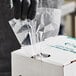 A person putting Choice extra heavy-duty plastic food bags into a white box.