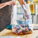 A person putting a bag of potatoes into a Choice extra heavy-duty plastic food bag.