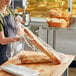 A woman holding a Choice plastic food bag with a baguette inside.