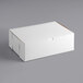 A 14" x 10" x 5" white bakery box with a lid on a gray surface.