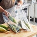 A person holding a Choice heavy-duty plastic food bag filled with corn.
