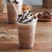 A close-up of a chocolate mocha drink with whipped cream and chocolate chips with a straw.