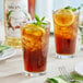 A glass of Monin Premium Pure Cane Syrup iced tea with a lemon slice and mint leaves.