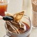 A person pouring illy Cold Brew into a plastic cup with a straw.