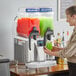 A woman pouring a drink from a Bunn Ultra NX slushy machine.