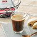 A glass of illy espresso with a spoon and a biscuit on the side.