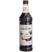 A close up of a Monin Dark Chocolate syrup bottle filled with dark liquid.