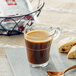 A glass of illy coffee on a table with a cookie.