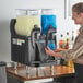 A woman pouring a blue drink into a Bunn slushy machine.