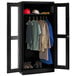 A black Tennsco wardrobe cabinet with clear doors filled with clothes.