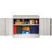 A light gray Tennsco metal storage cabinet with books and boxes inside.