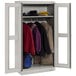 A light gray Tennsco wardrobe cabinet with C-Thru doors holding clothes.