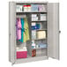 A light gray Tennsco metal combination cabinet with solid doors and items on the shelves.