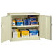 A Tennsco putty storage cabinet with solid doors open and filled with blue and yellow boxes.