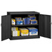 A black metal Tennsco jumbo storage cabinet with solid doors and shelves full of boxes.